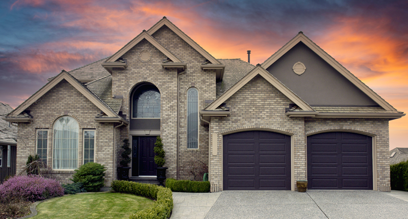 exterior greay brick home with two garage doors